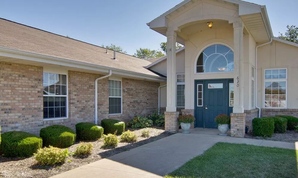 A well-maintained building entrance with neatly trimmed bushes and a welcoming pathway.