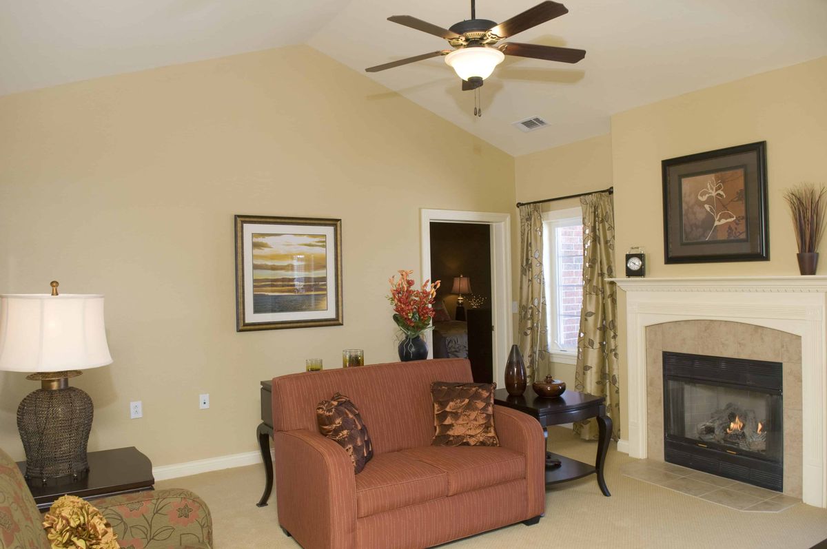 A cozy living room featuring a sofa, ceiling fan, and fireplace with elegant decor.