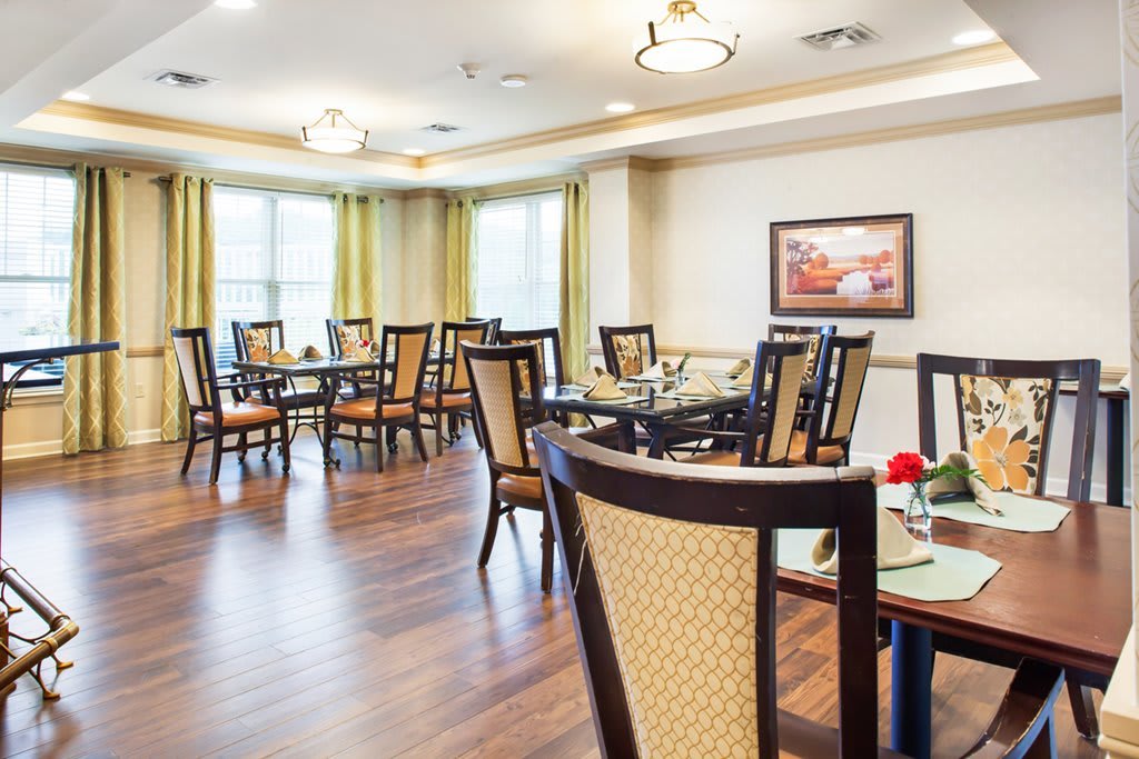 A modern dining area with elegant tables and chairs, featuring wood flooring and bright lighting.