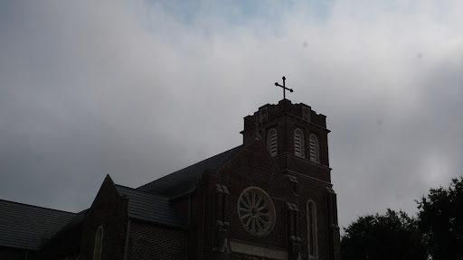 A solemn church building silhouetted against a cloudy sky.