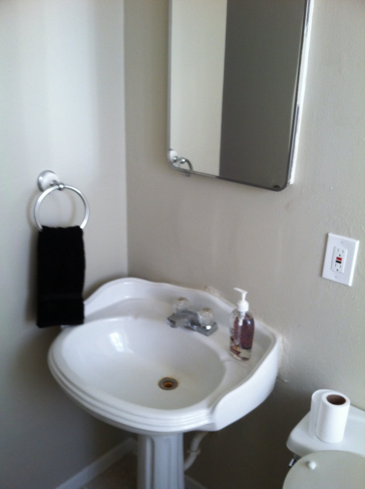 A small bathroom with a sink, mirror, and essential toiletries.