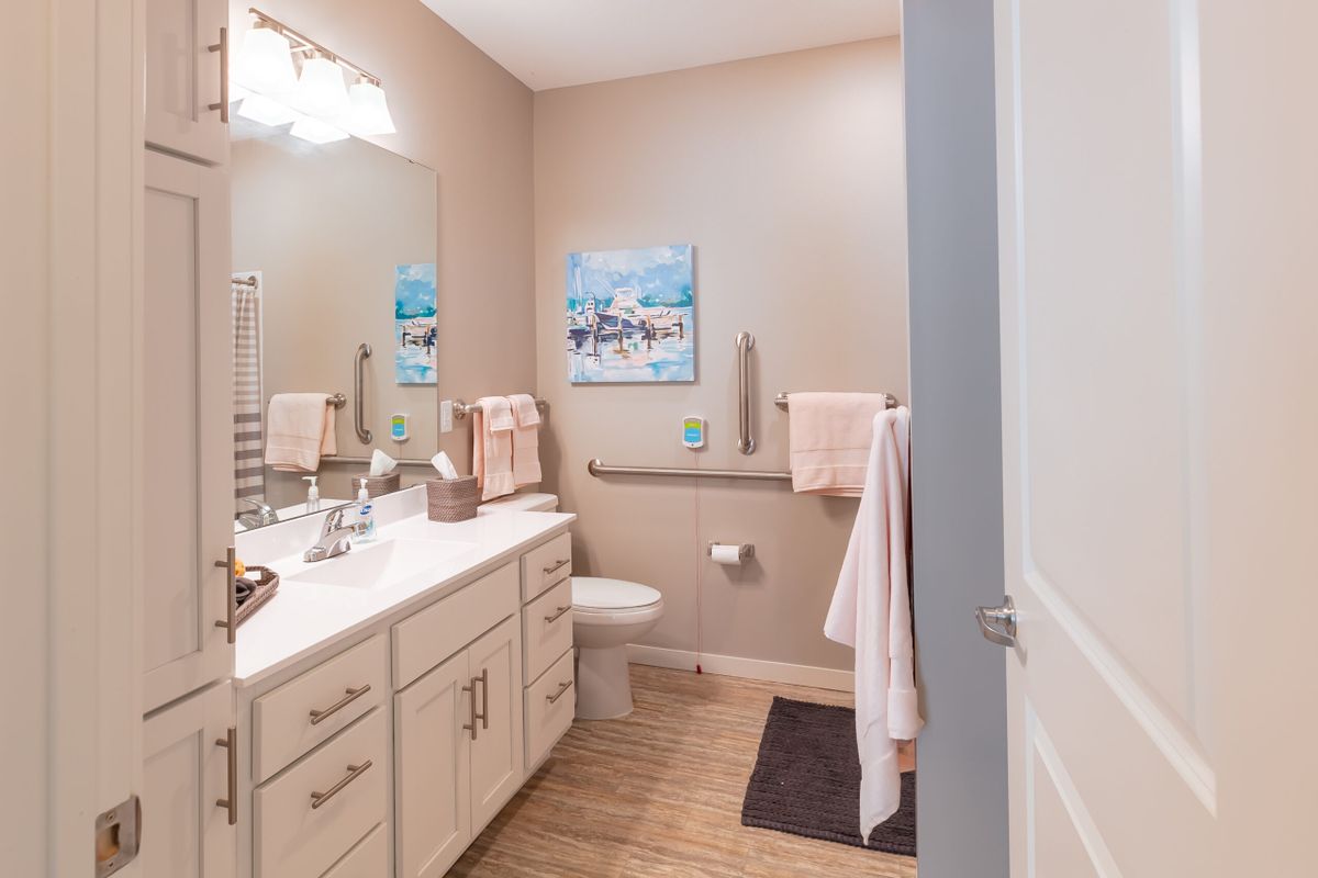 A modern bathroom with neutral tones and tasteful decor, featuring a sink, toilet, and wall art.