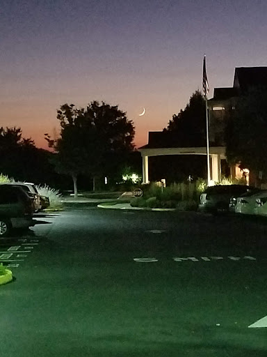 A serene evening view of a well-lit parking area with trees silhouetted against the twilight sky.