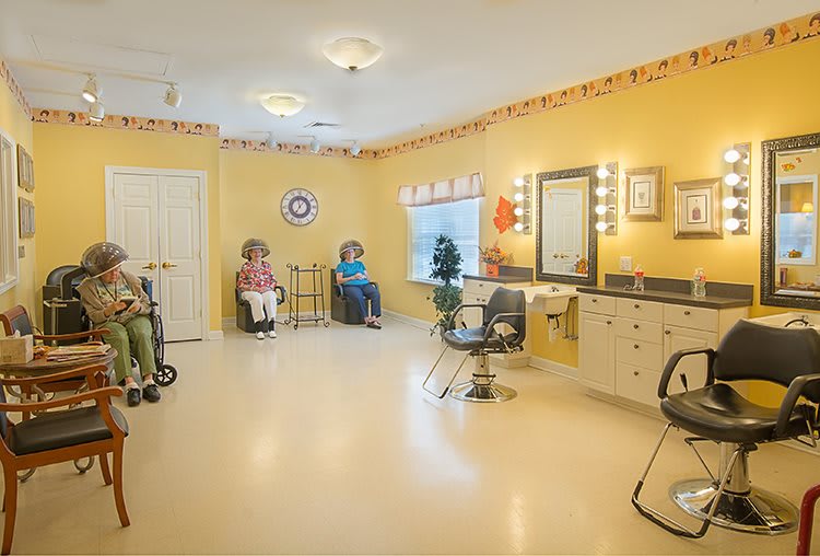 An empty salon with chairs and mirrors, featuring yellow walls and a waiting area.