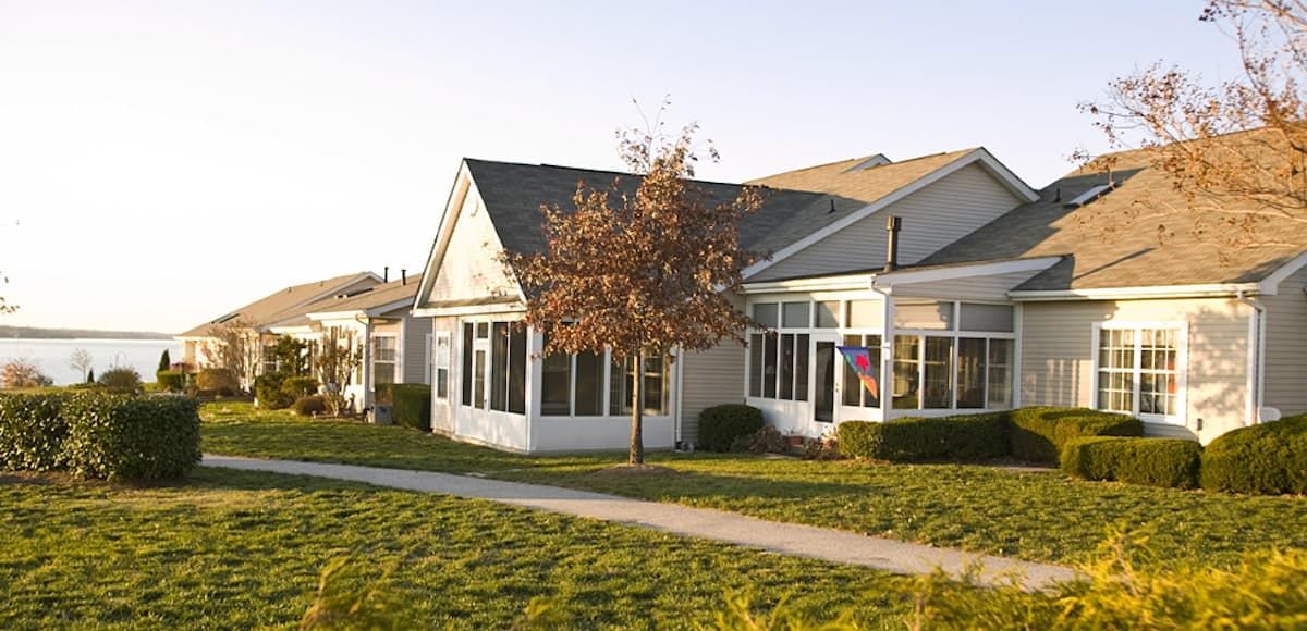 A suburban house with a well-maintained lawn and trees, lit by daylight.