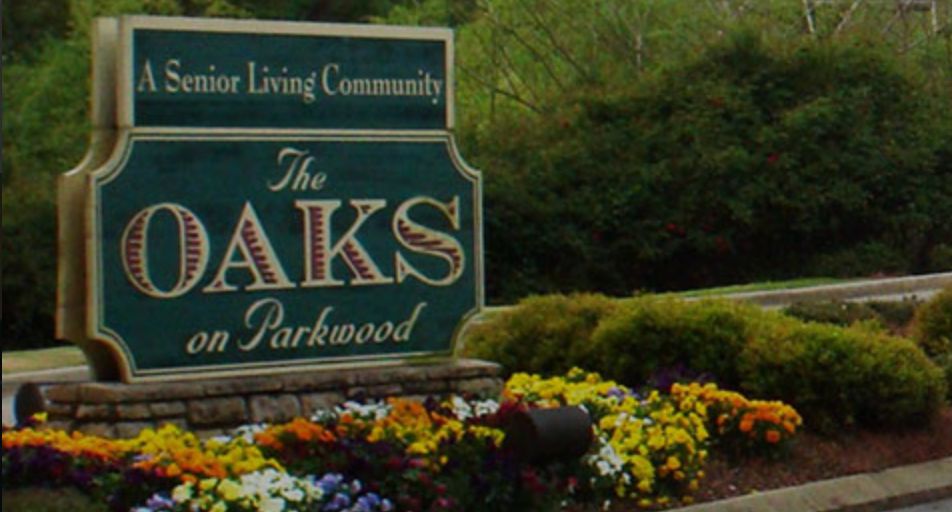 Community entrance sign surrounded by flowers.