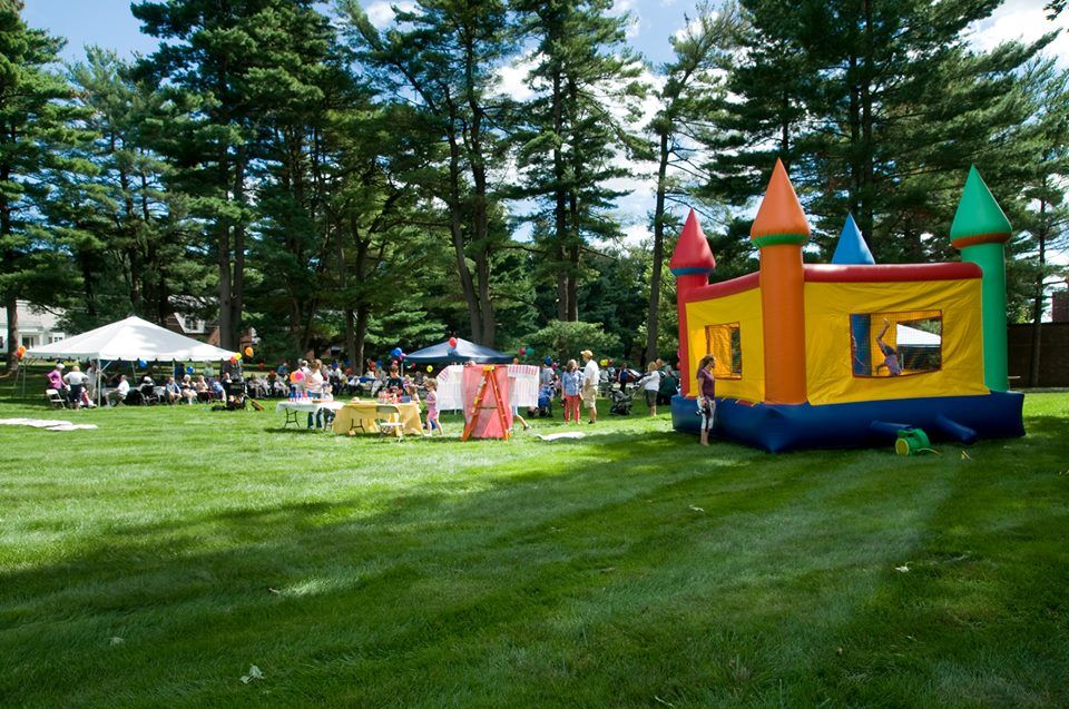 A lively outdoor festival featuring a colorful bounce house on a sunny day.