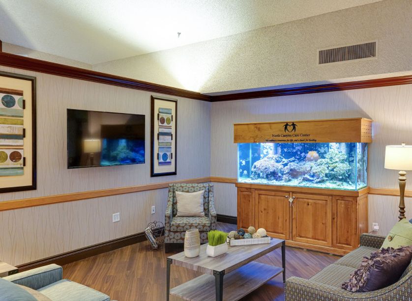 A modern living room with a large aquarium as a centerpiece, complemented by comfortable seating and a wall-mounted television.