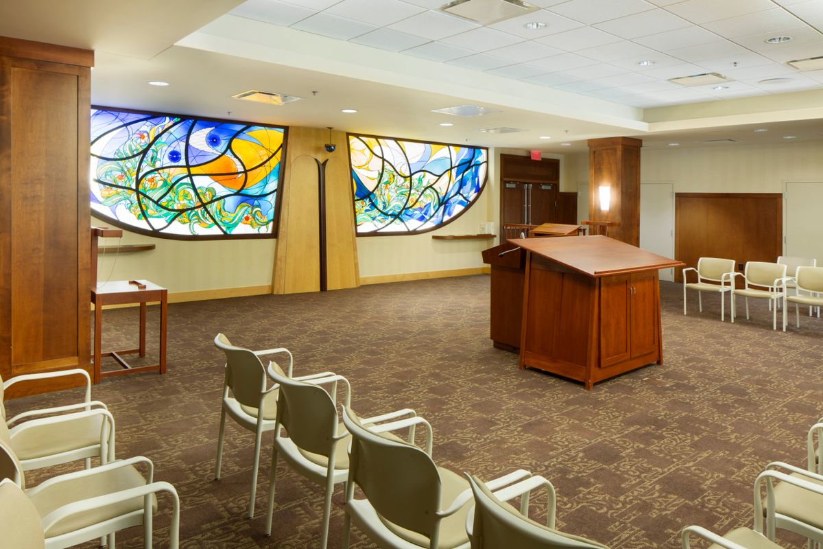 A small chapel with stained glass windows and seating for worship.