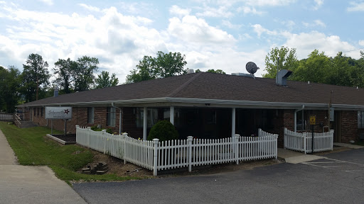 A charming single-story house surrounded by a white picket fence under a partly cloudy sky.