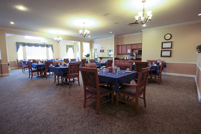 A spacious dining area with neatly arranged tables and chairs, illuminated by elegant chandeliers.