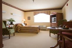 A spacious hotel room with a bed, TV, and seating area.