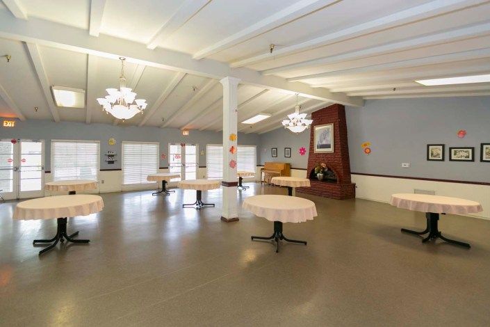 An empty room with tables, chairs, and chandeliers.