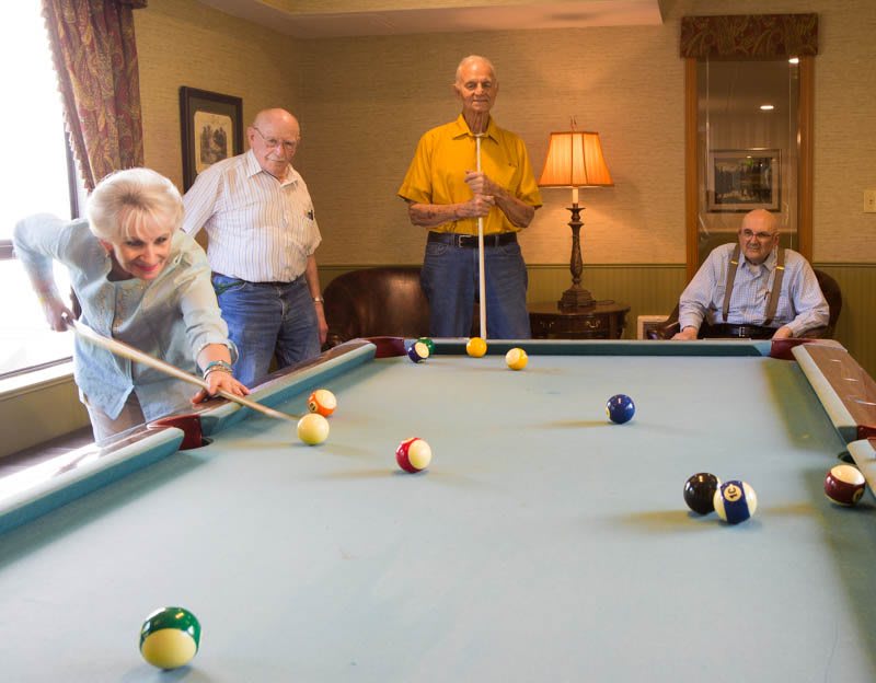 A group of seniors enjoying a game of billiards together.