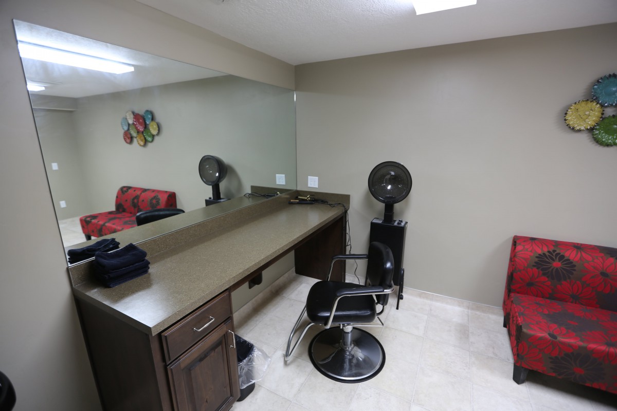 A salon workspace featuring a styling chair, large mirror, and hair dryer.