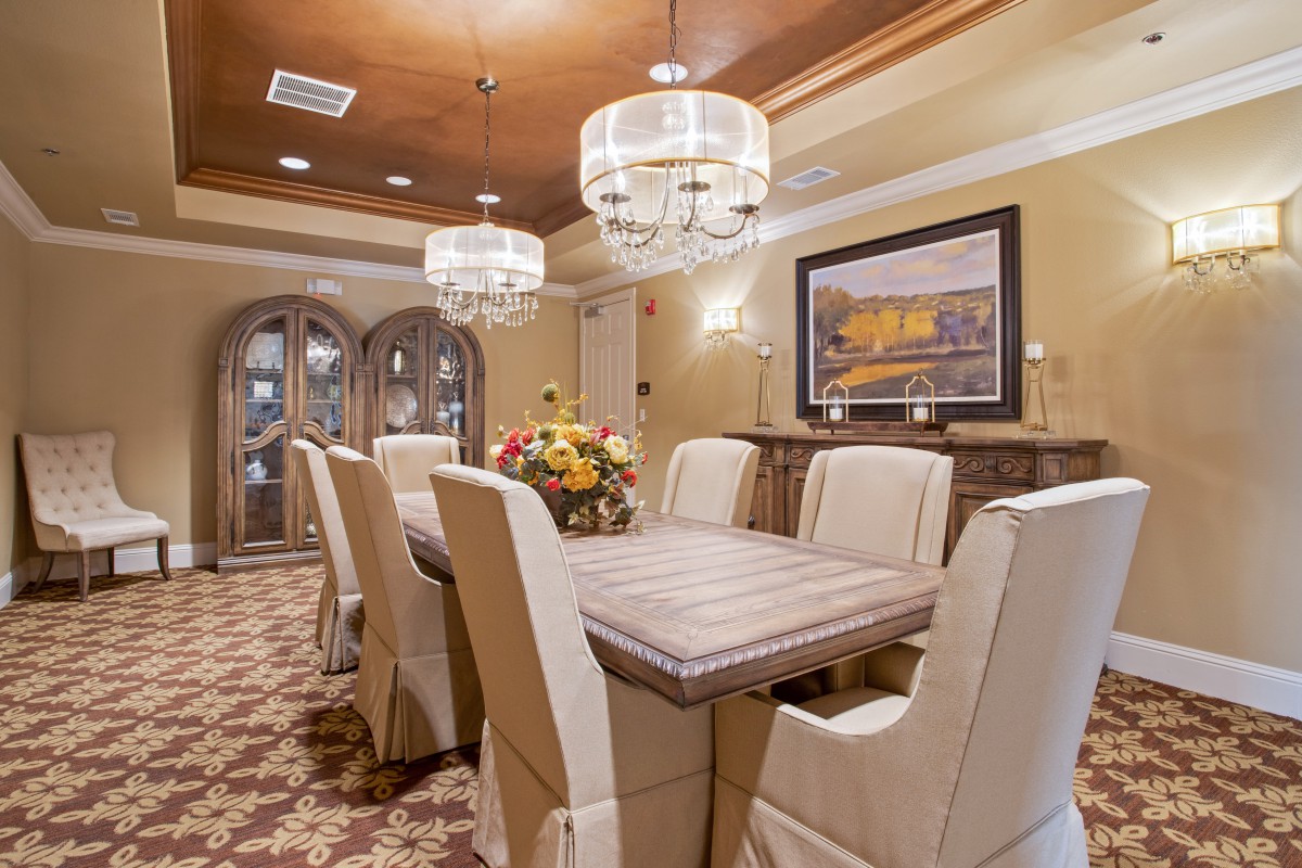 An elegantly designed dining room featuring a large table with upholstered chairs and ornate chandeliers.