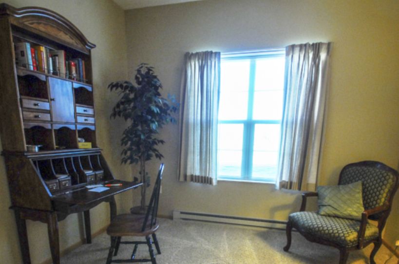 A cozy home office with a desk, chair, and natural light from the window.