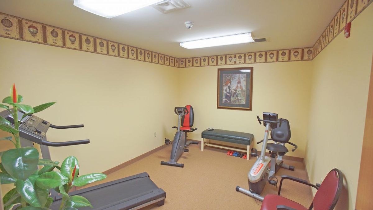 A small gym room with various fitness equipment including a treadmill and an exercise bike.