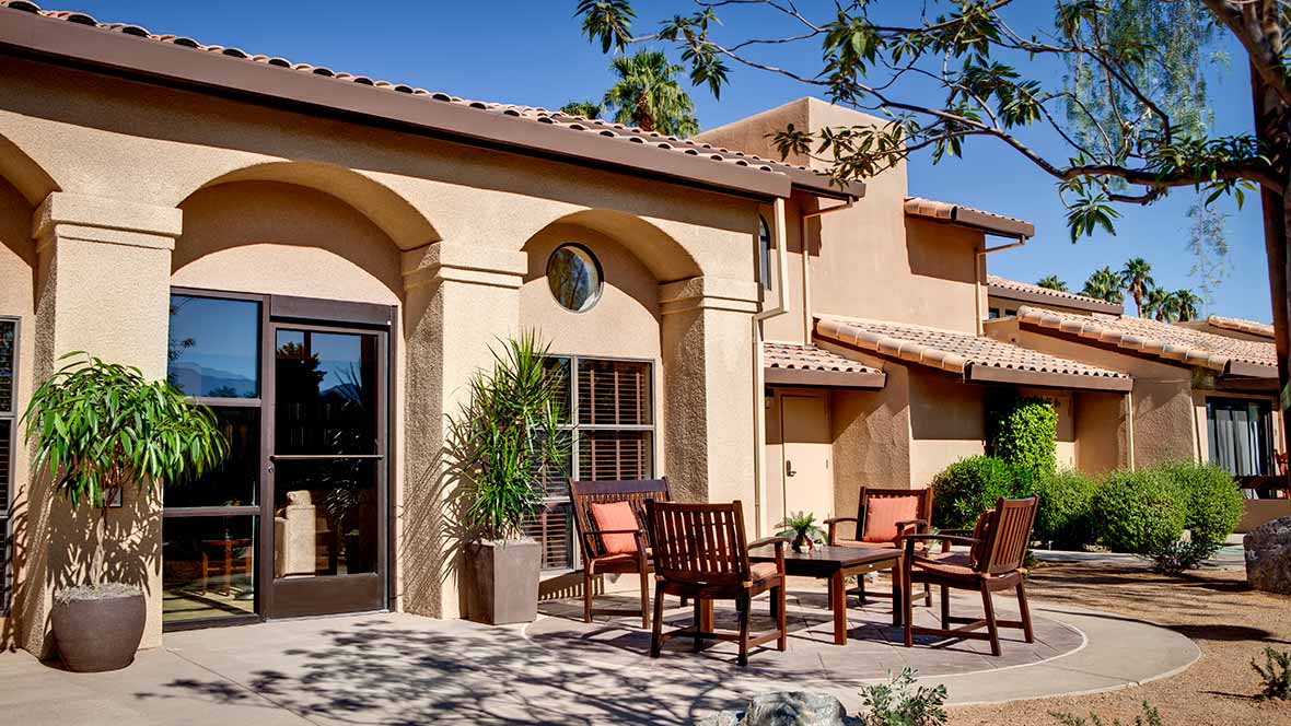 A Mediterranean-style building with outdoor seating on a sunny day.