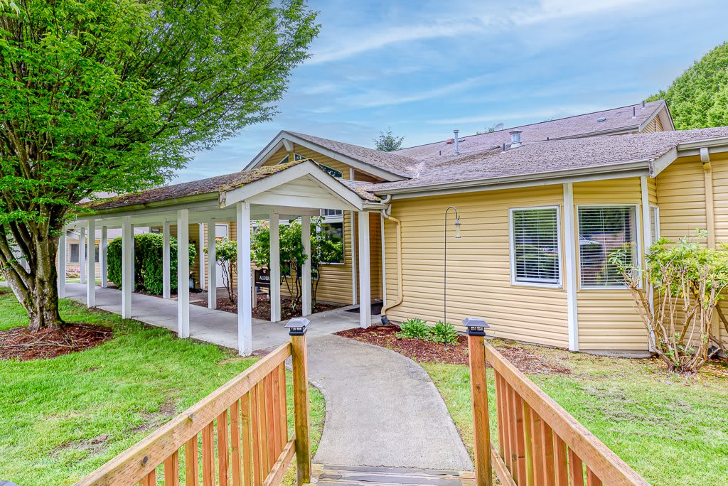 A charming yellow house with a small front porch and neatly landscaped yard.