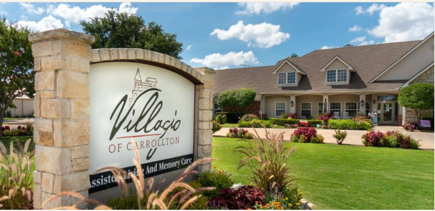 A retirement community sign in a well-landscaped area with a residential building in the background.