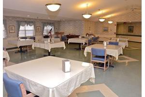 An empty dining room with tables and chairs arranged neatly under bright ceiling lights.
