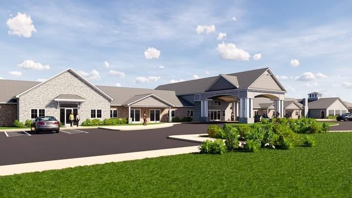A modern building with a landscaped garden and a spacious driveway under a partly cloudy sky.
