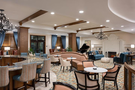 A stylish and inviting lounge area featuring comfortable seating, a grand piano, and warm lighting.