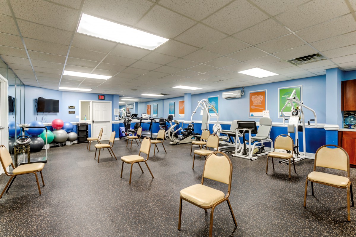 A spacious exercise room with chairs and gym equipment organized neatly.