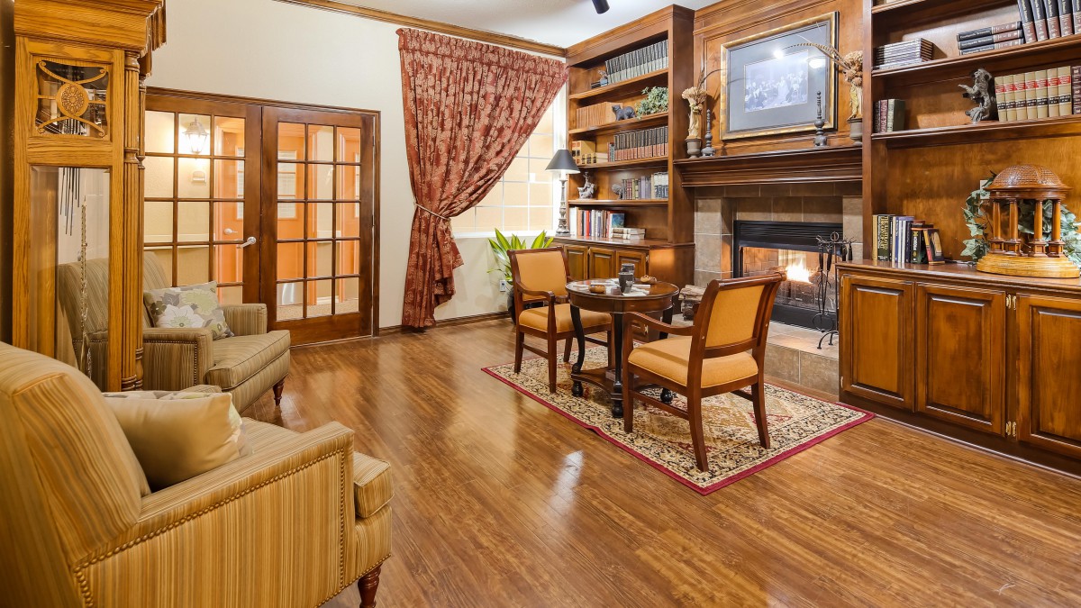 A cozy living room featuring a fireplace and wooden bookshelves, with comfortable seating and elegant decor.