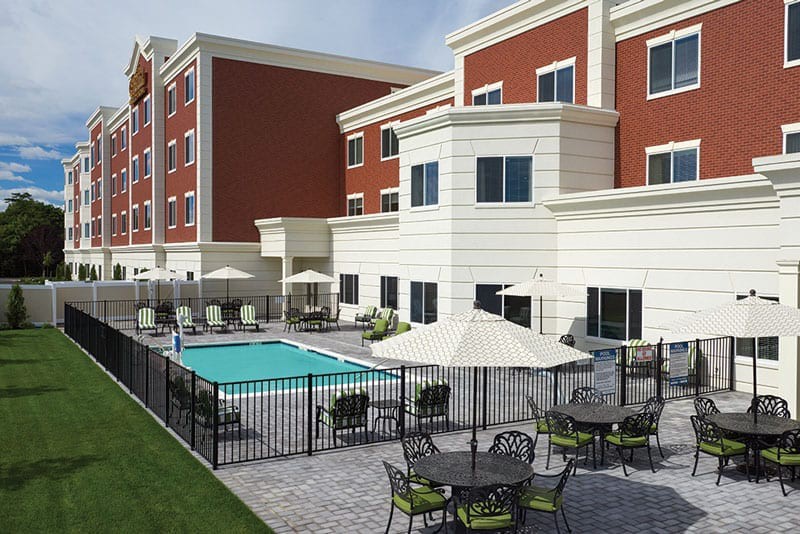 A modern hotel featuring an outdoor swimming pool and seating area with umbrellas.