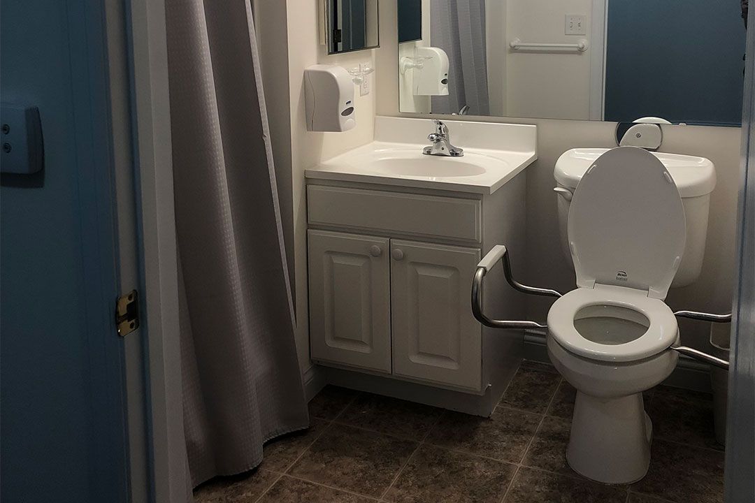 A small bathroom featuring a sink, toilet, and shower with a gray curtain.