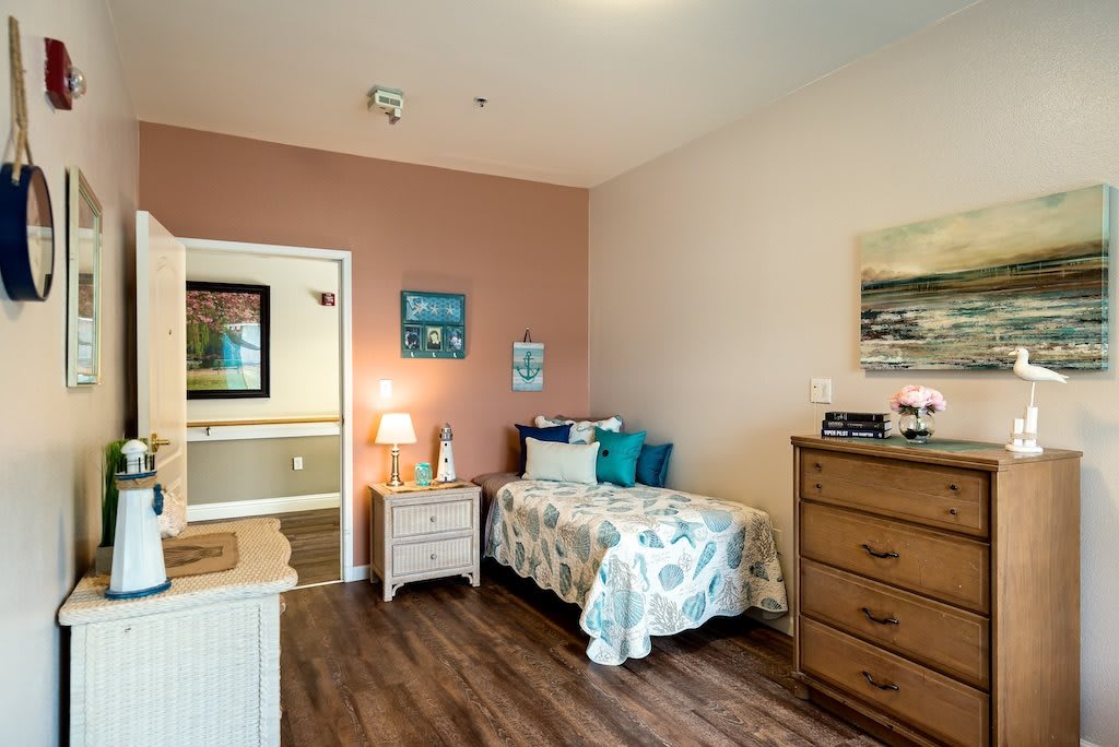 A cozy bedroom with a single bed, wooden furniture, and decorative elements.