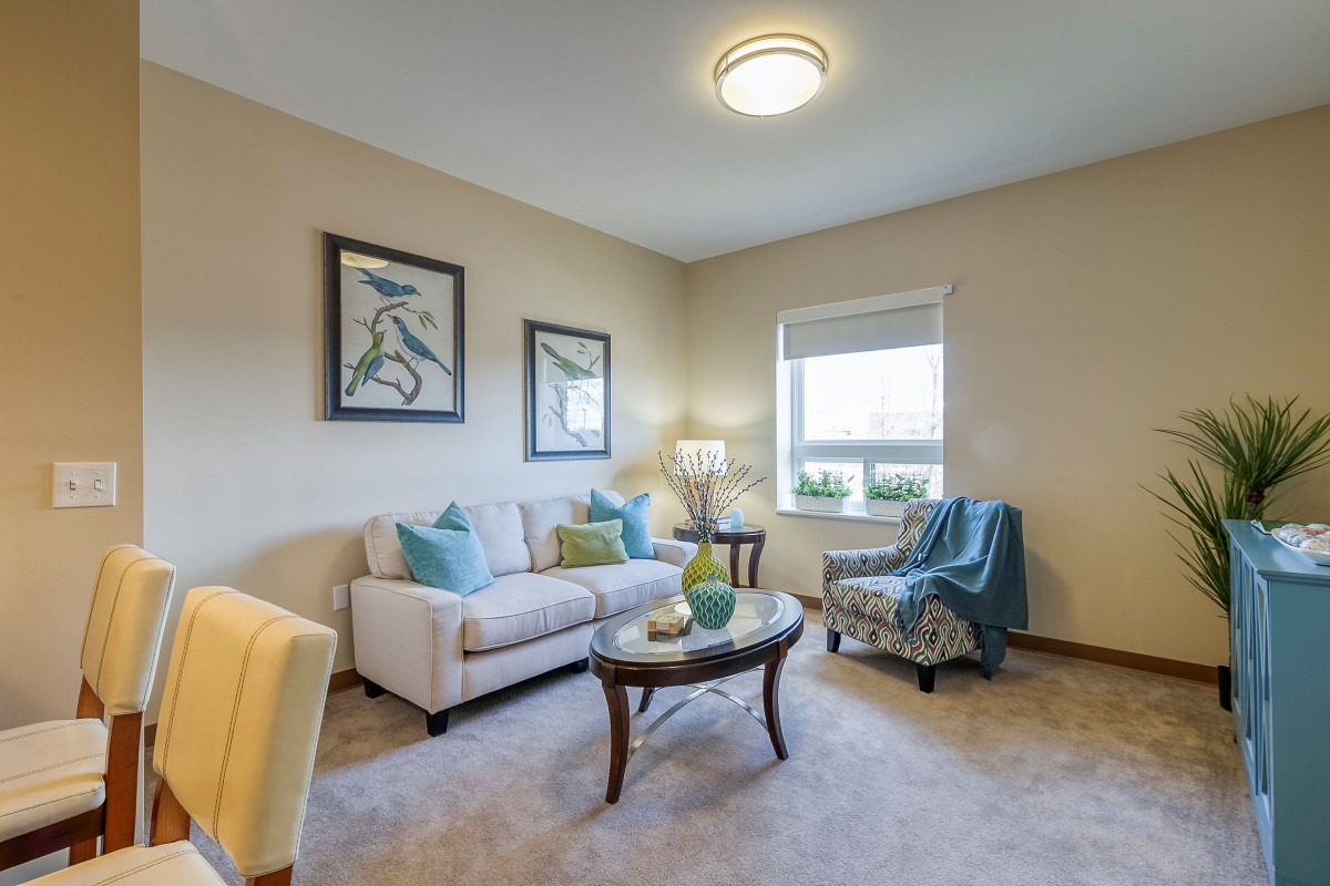 A cozy living room with a neutral color palette, featuring a sofa, coffee table, and decorative artworks on the wall.