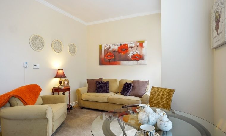 A cozy living room with a sofa, colorful artwork, and a stylish coffee table setup.