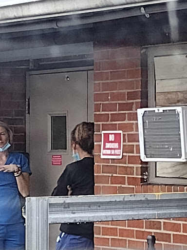 Two individuals engaged in a conversation outside a healthcare facility.