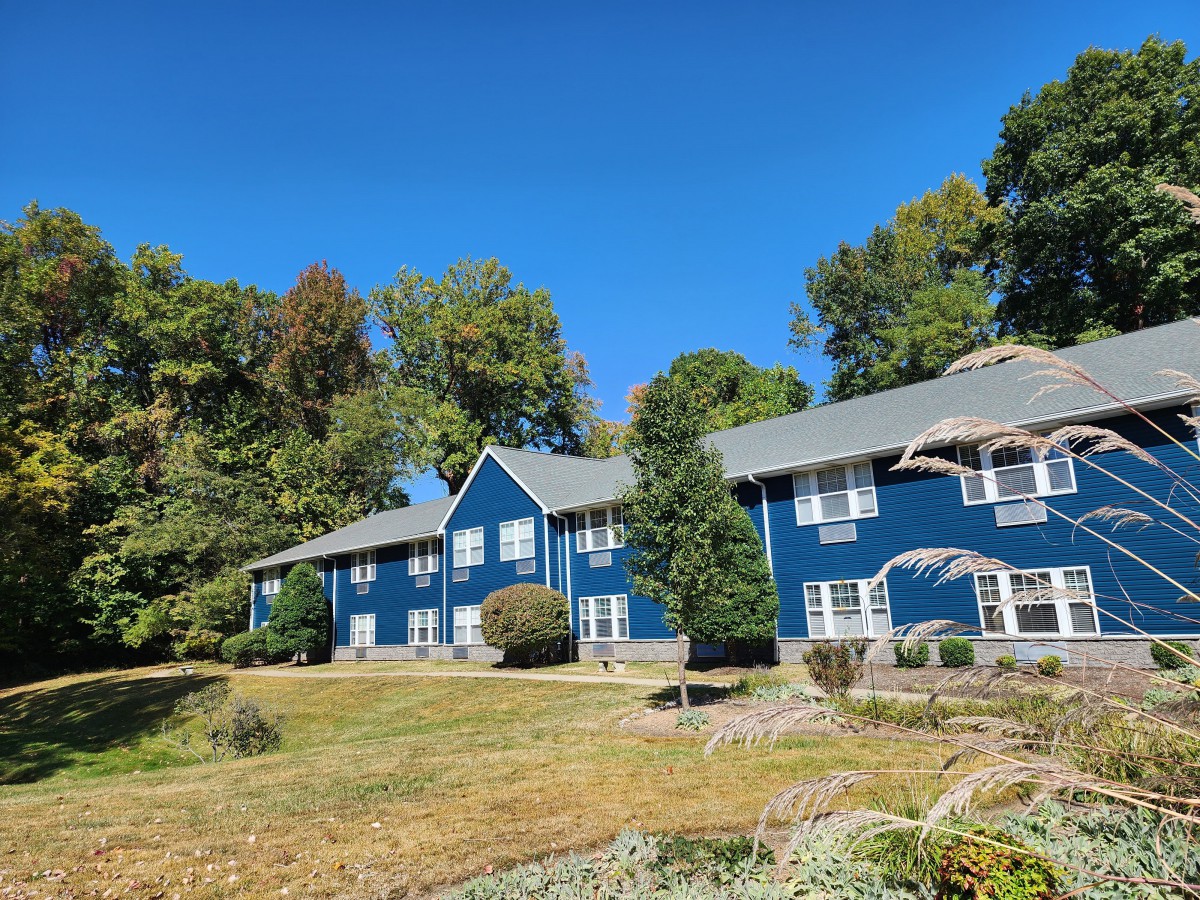 A blue residential building surrounded by greenery on a sunny day.