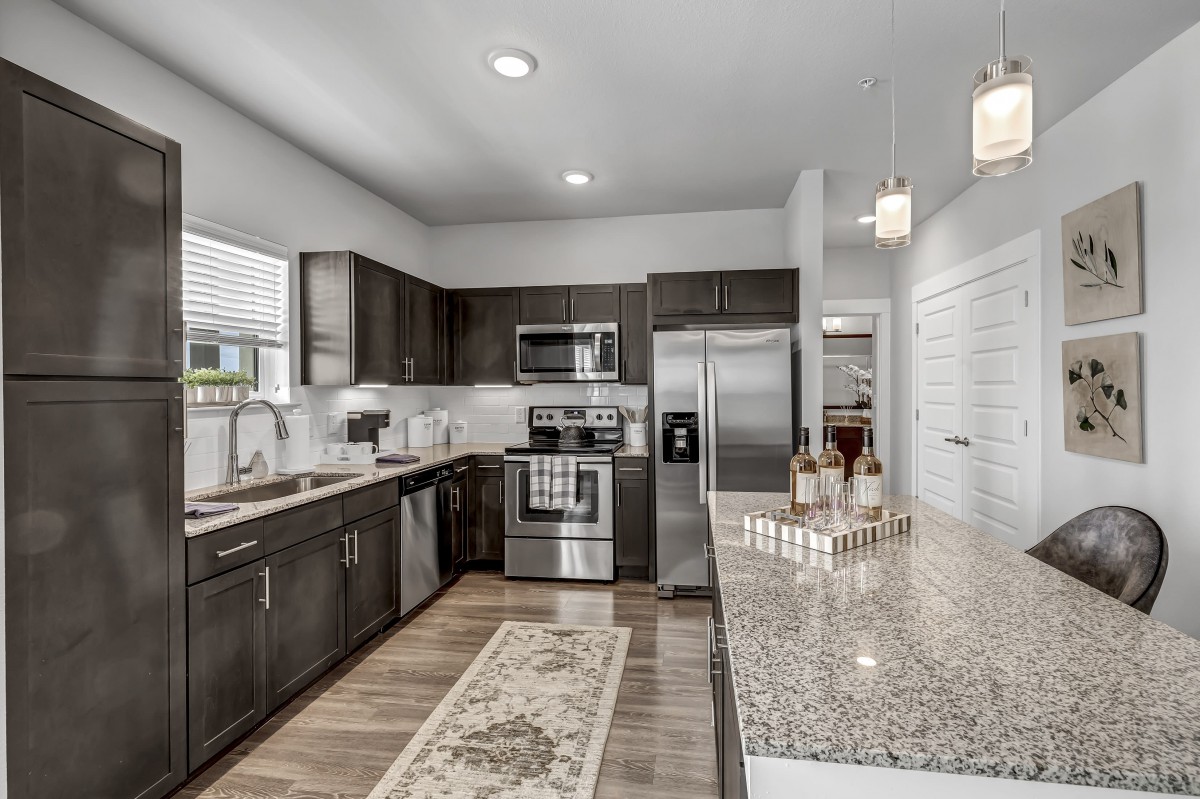 A modern kitchen featuring stainless steel appliances, granite countertops, and dark wood cabinets.