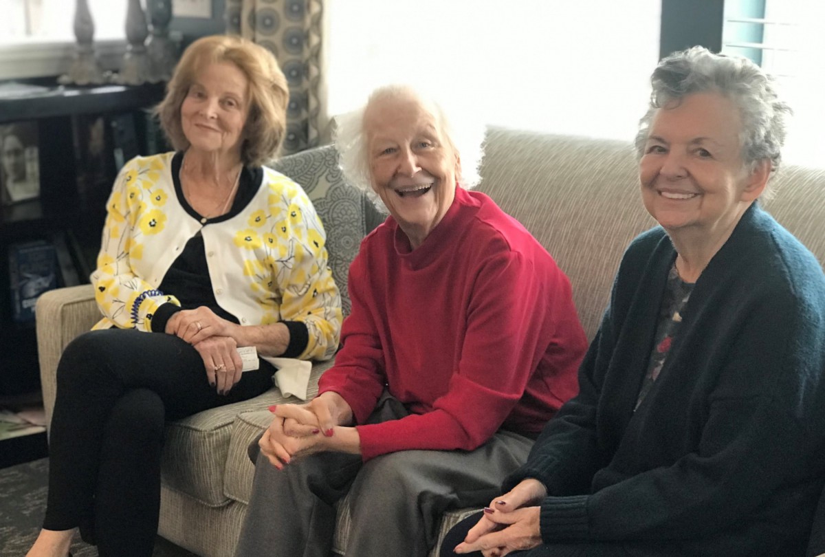 A group of women sitting together and smiling indoors.