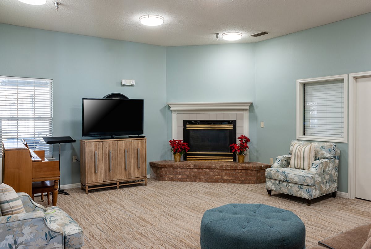 A cozy living room with a television and fireplace, featuring comfortable seating and minimalist decor.