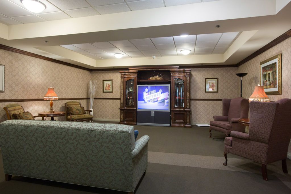 A cozy living room with a television, sofa, and chairs arranged for comfortable viewing.