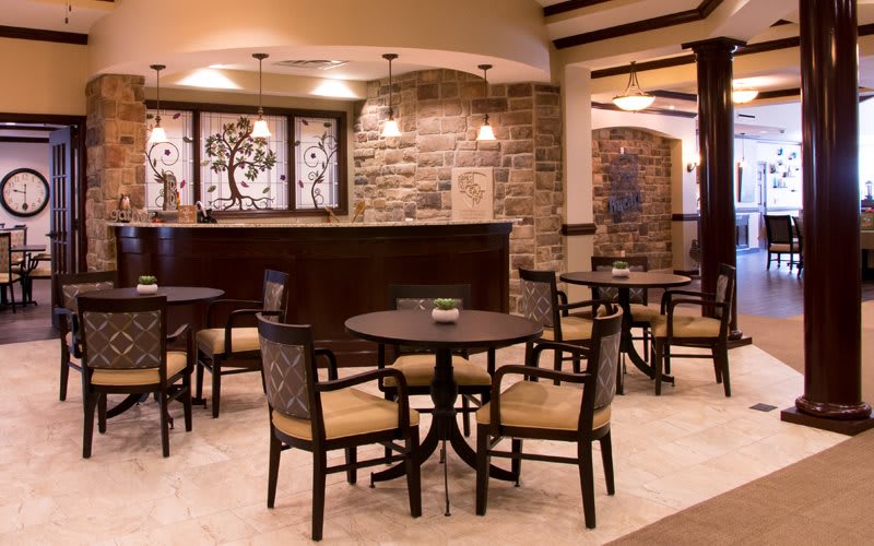 A cozy lobby interior with tables and chairs arranged for seating, featuring modern decor with brick walls and warm lighting.