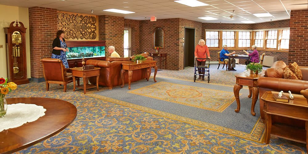 A spacious and well-furnished retirement home common area with seniors engaging in leisure activities.