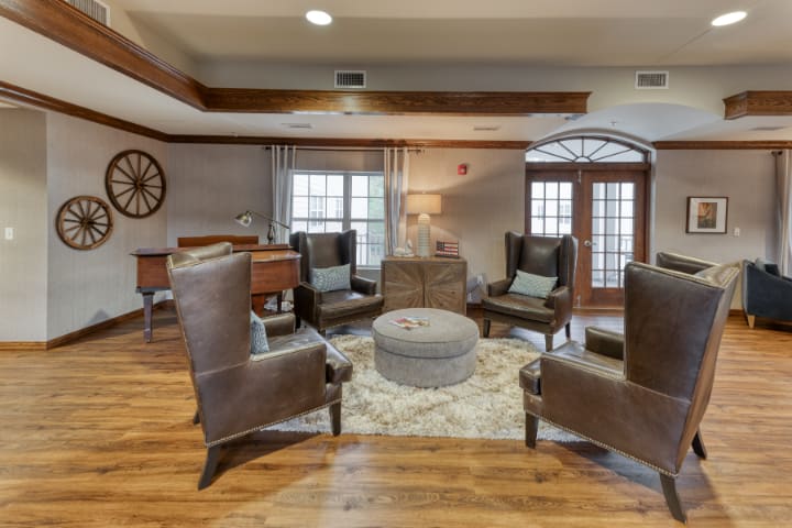 A cozy living room with leather armchairs arranged around a round coffee table on a patterned rug.