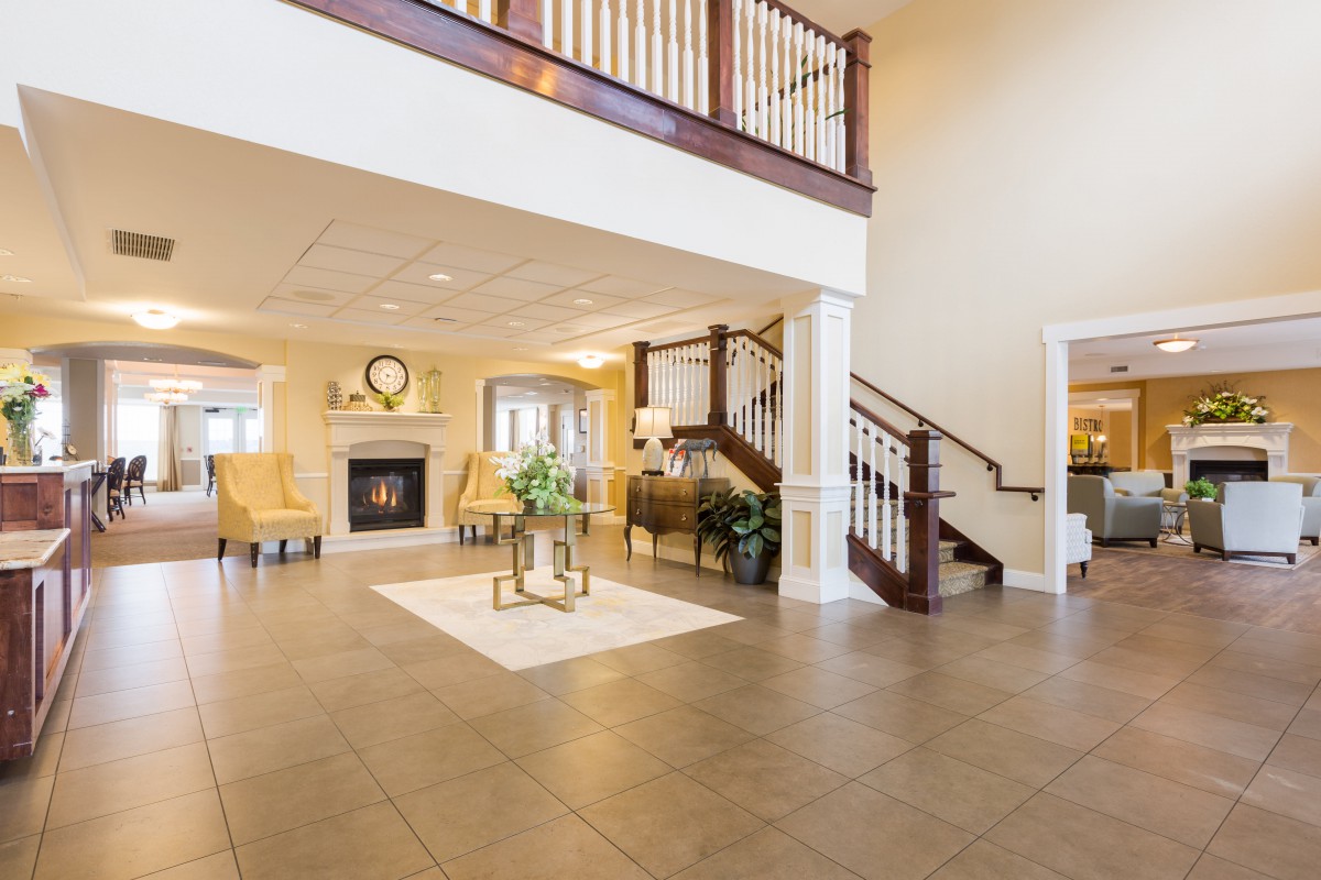 A spacious foyer with a staircase, featuring elegant decor and a cozy seating area near a fireplace.
