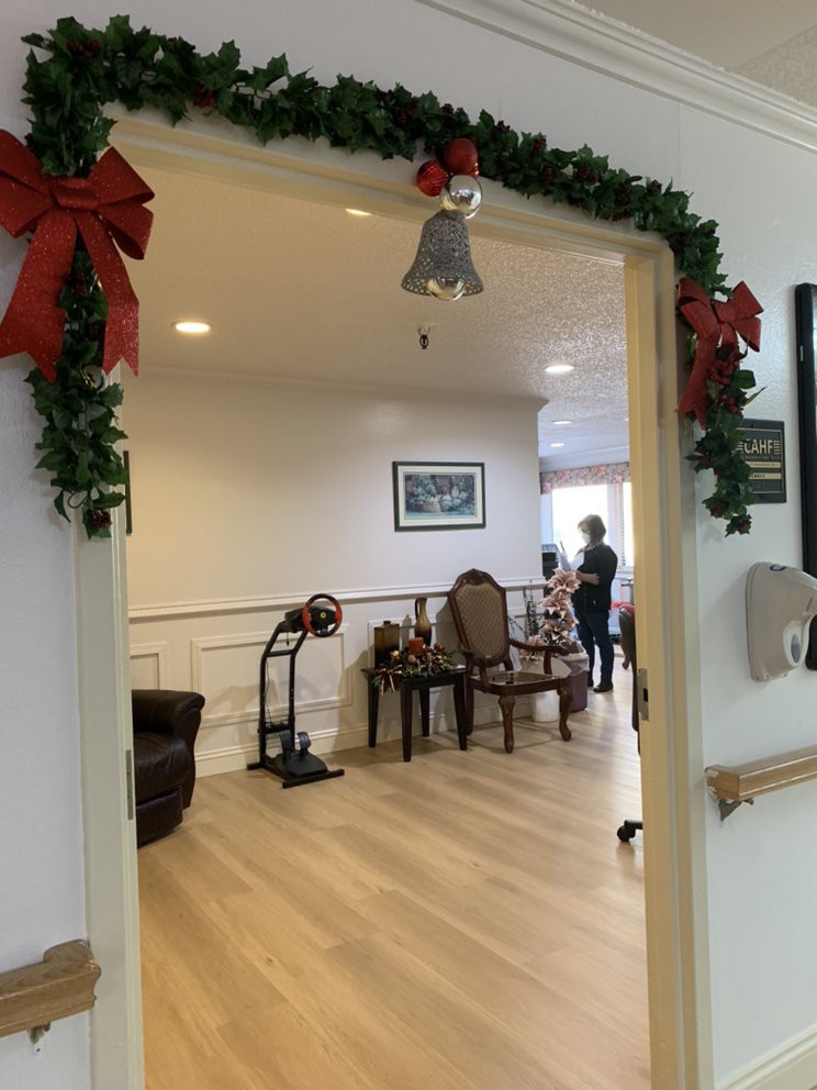 A cozy indoor space adorned with Christmas decorations, featuring a garland and bows around the entrance.