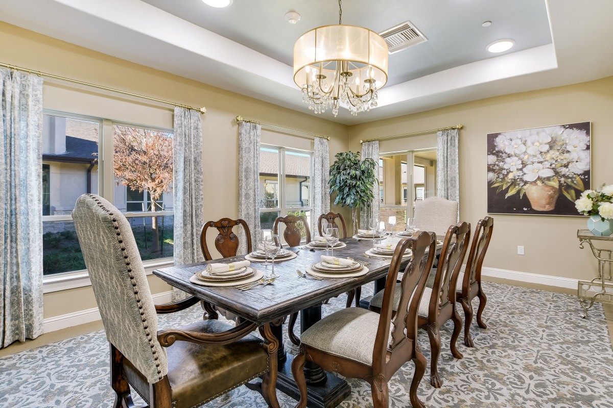 An elegant dining room with a beautifully set table and ornate chairs, illuminated by a stylish chandelier.