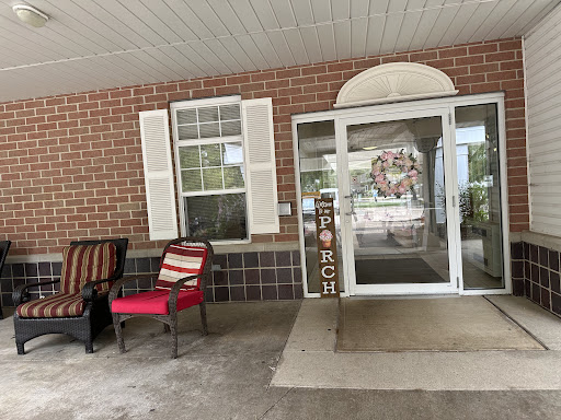 A cozy porch area featuring a welcoming entrance with a red chair and decorative elements.