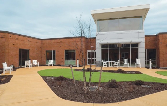 A modern courtyard with seating and landscaping outside a brick building.