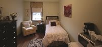 A cozy bedroom with a single bed and an armchair by the window.